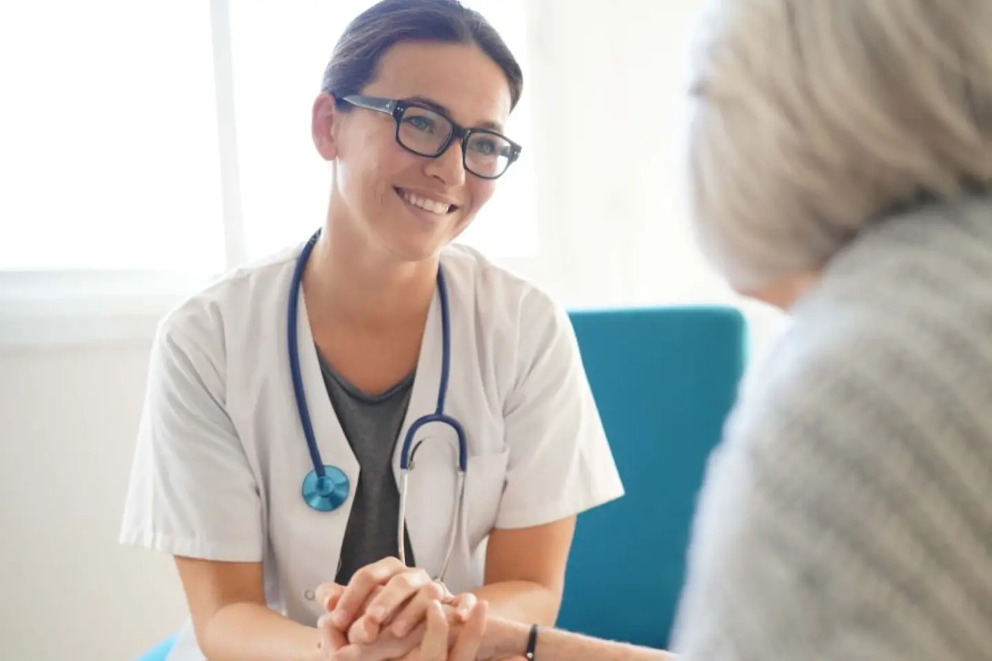 Smiling doctor holding elderly patients hand, native AWS services to enhance security