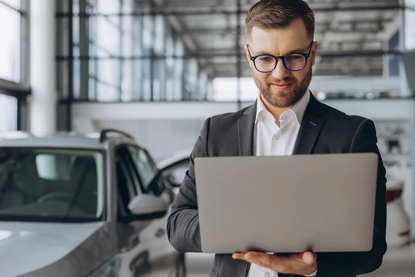 Um vendedor de carros com um laptop em uma concessionária de automóveis