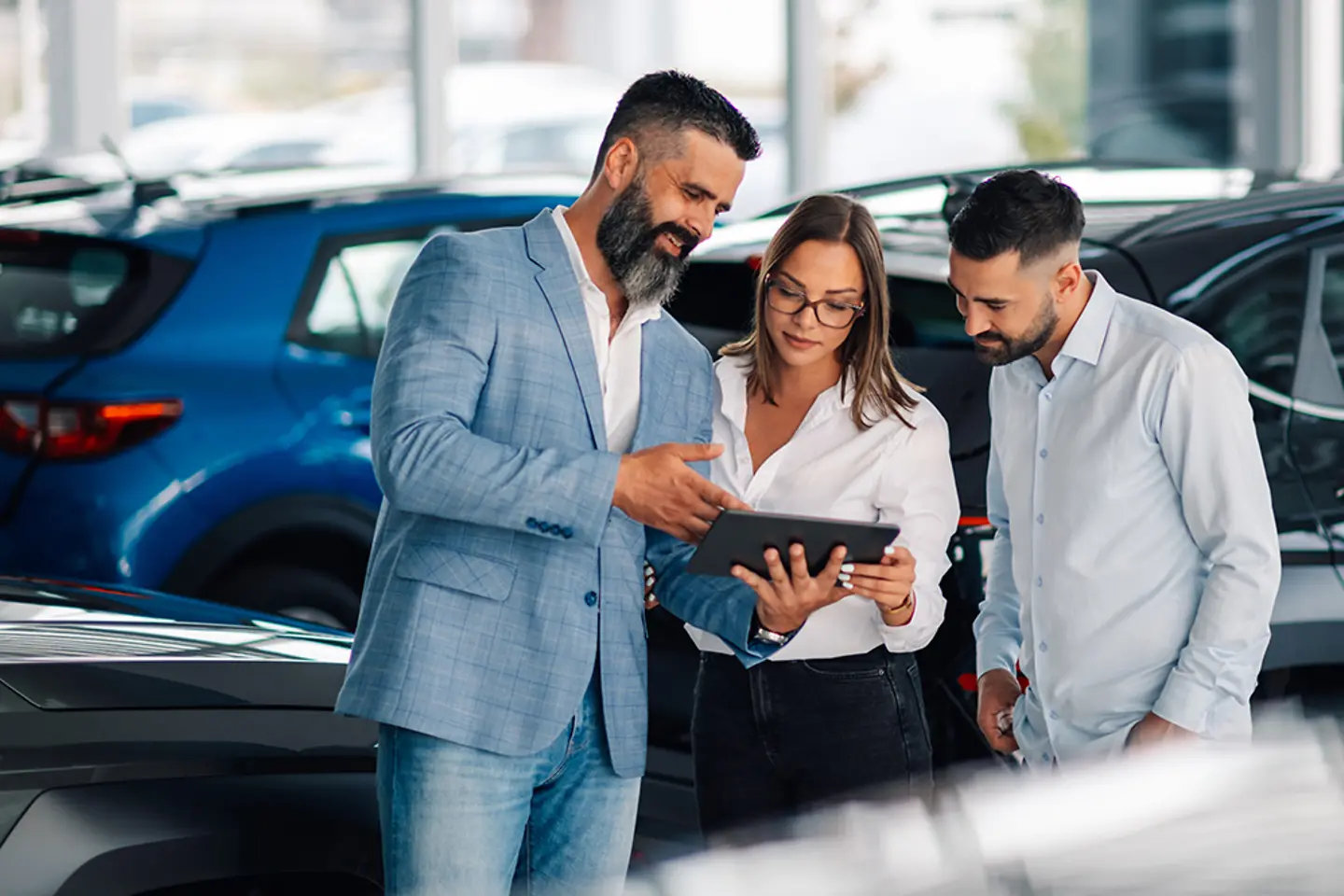Comerciante utilizando una tableta para mejorar el proceso de compra de un coche por parte de una pareja.