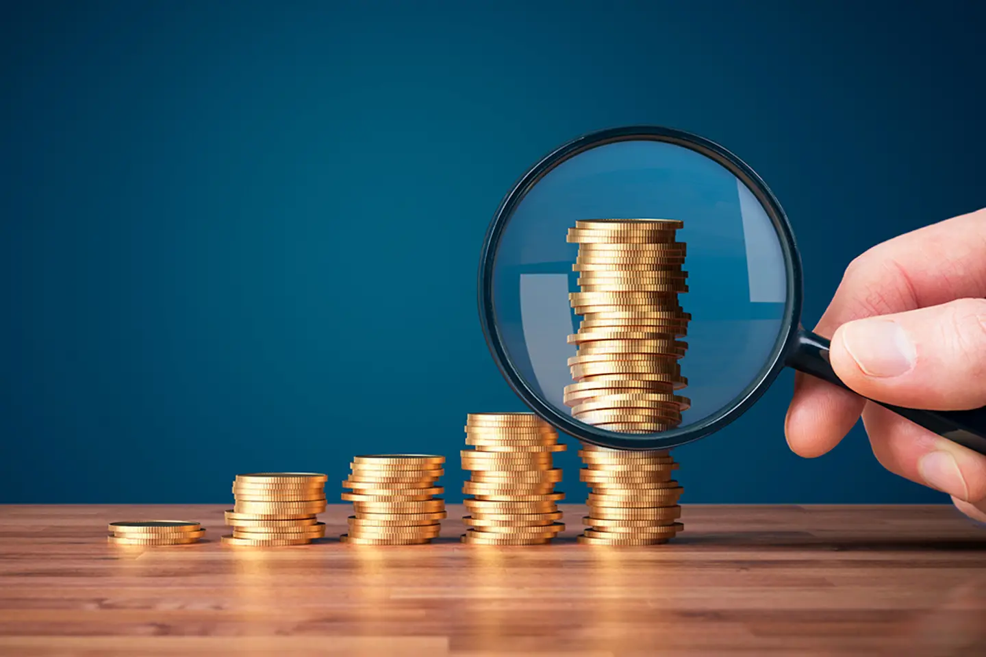 Moedas empilhadas com uma lupa em primeiro plano