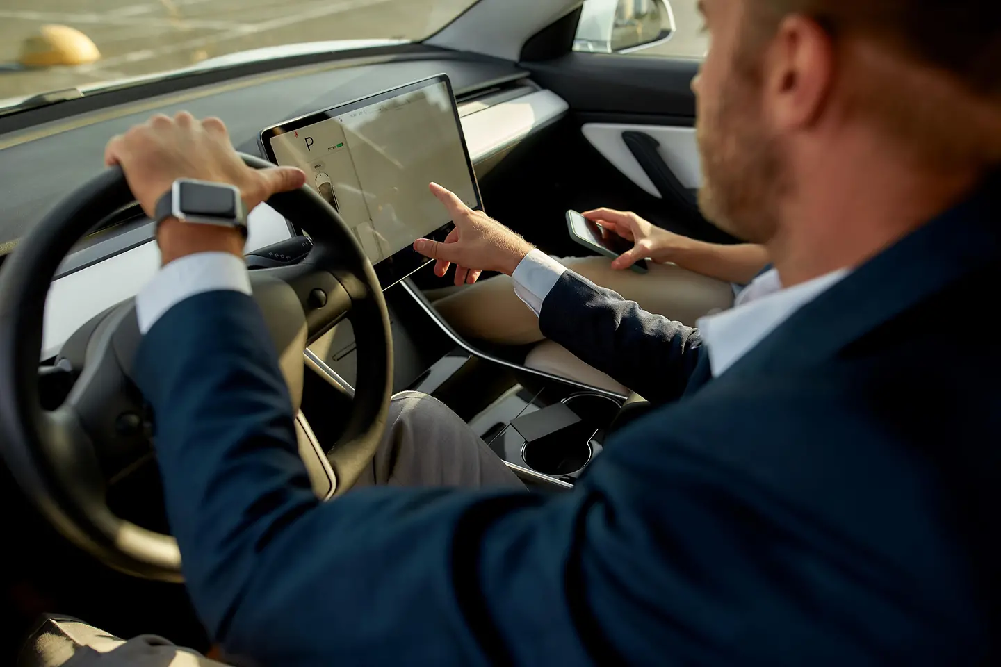 Junger hellhäutiger Mann berührt den Bordcomputerbildschirm in einem Auto.