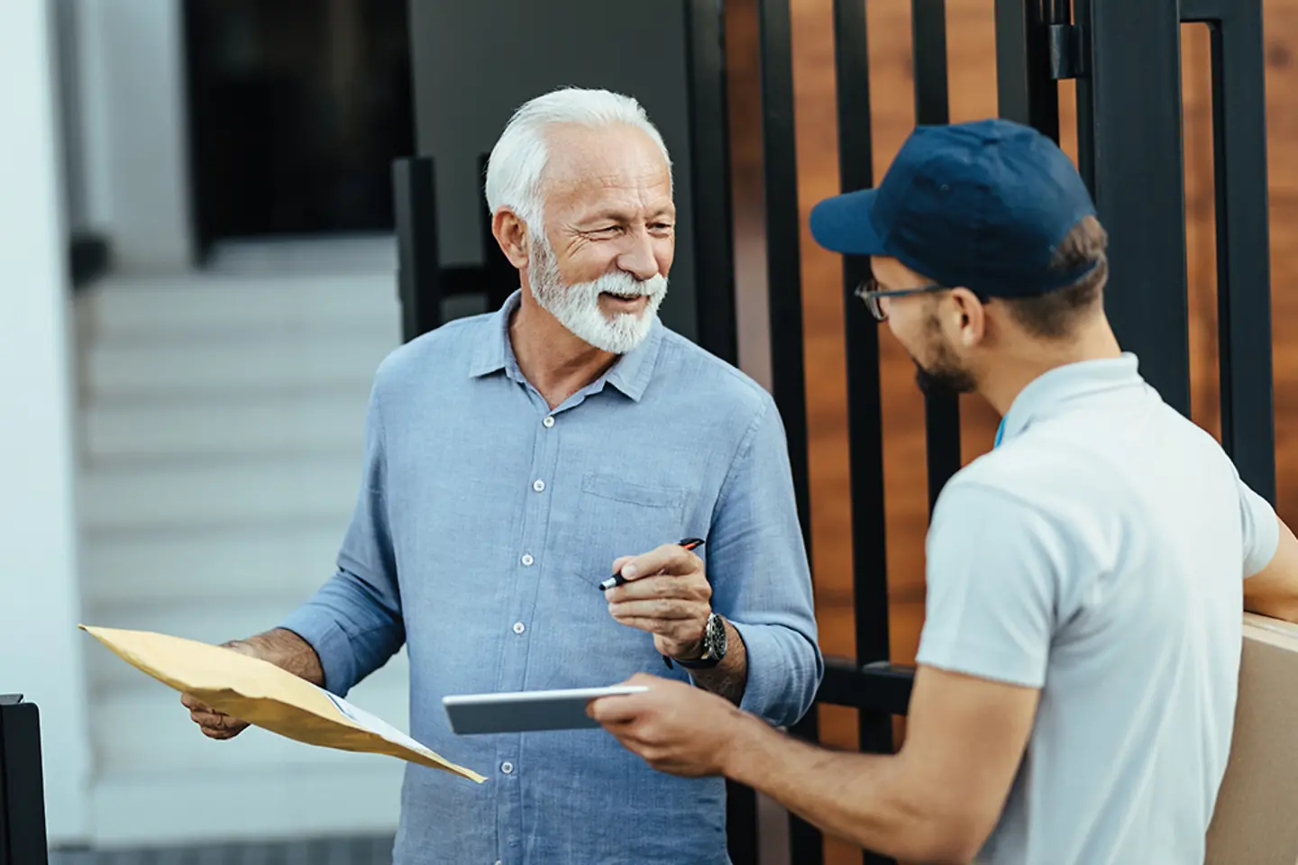 Parcel carrier man delivering a packet to an elderly man