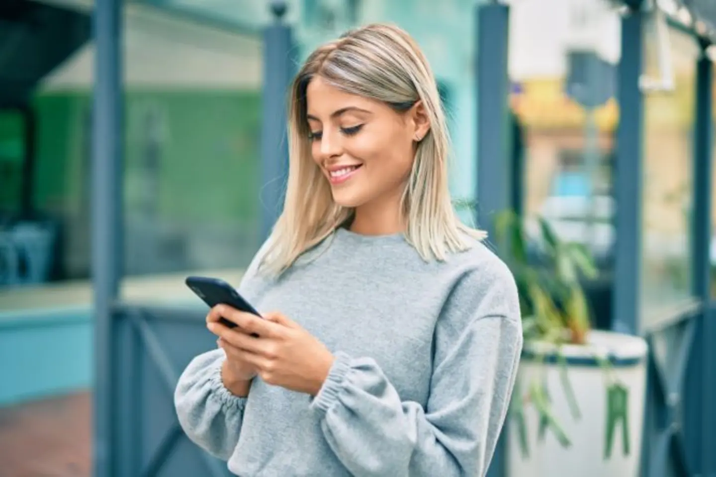 Smiling citizen using public administration smart chat on her smartphone in city