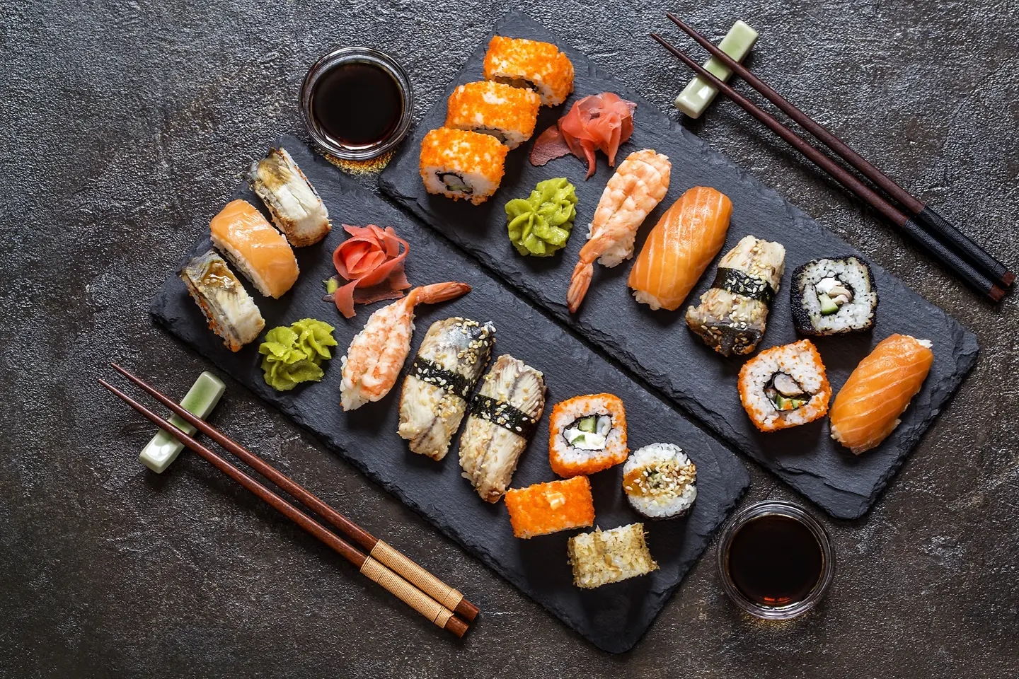 Sushi Rollen mit Reis, Fisch, Sojasauce auf einem dunklen steinernern Hintergrund