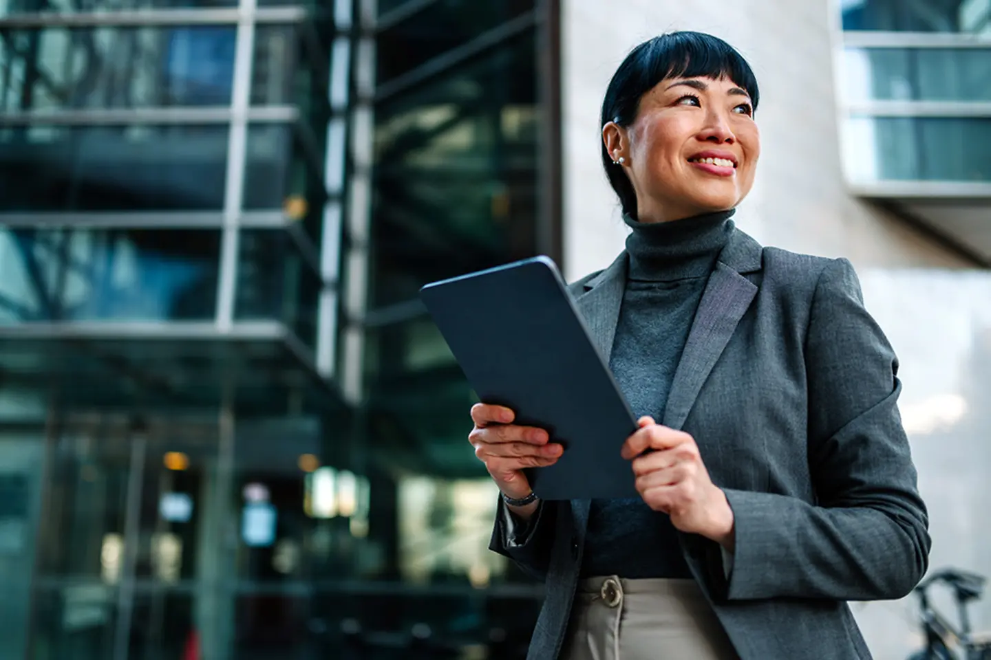 A smiling businesswoman holds a tablet computer
