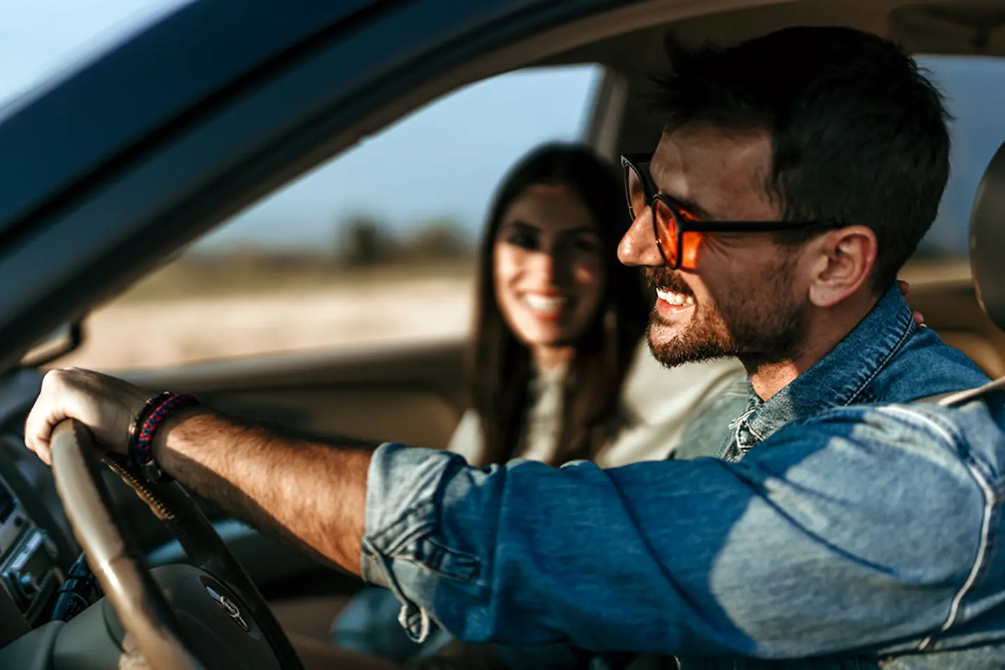 Happy couple driving together in a car, enjoying a scenic sunset on a road trip 