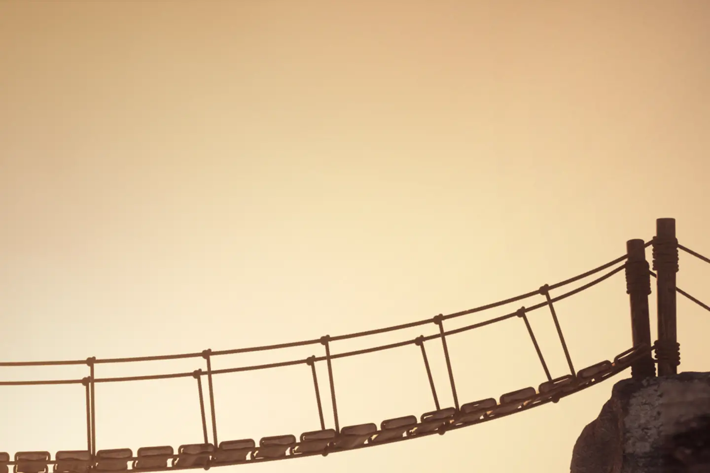 A hiker crossing a suspended bridge linking two mountain peaks