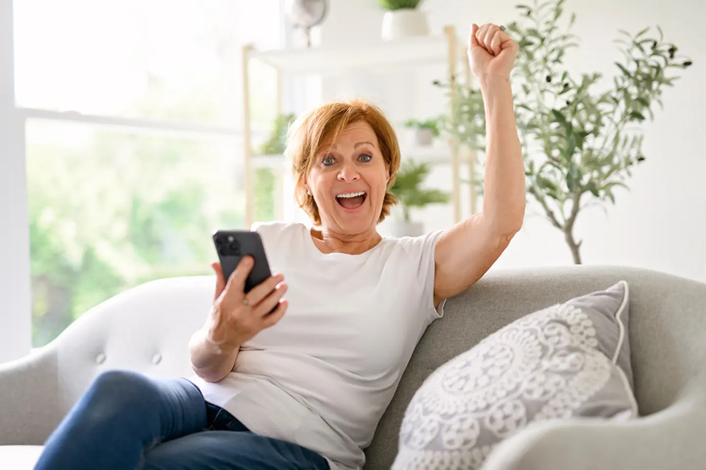 Un mujer alegre con un smartphone en mano.