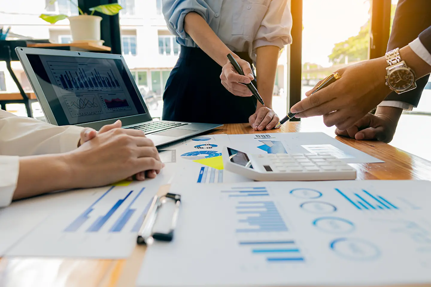 A financial group of business people is meeting to analyze data for a marketing plan on a table