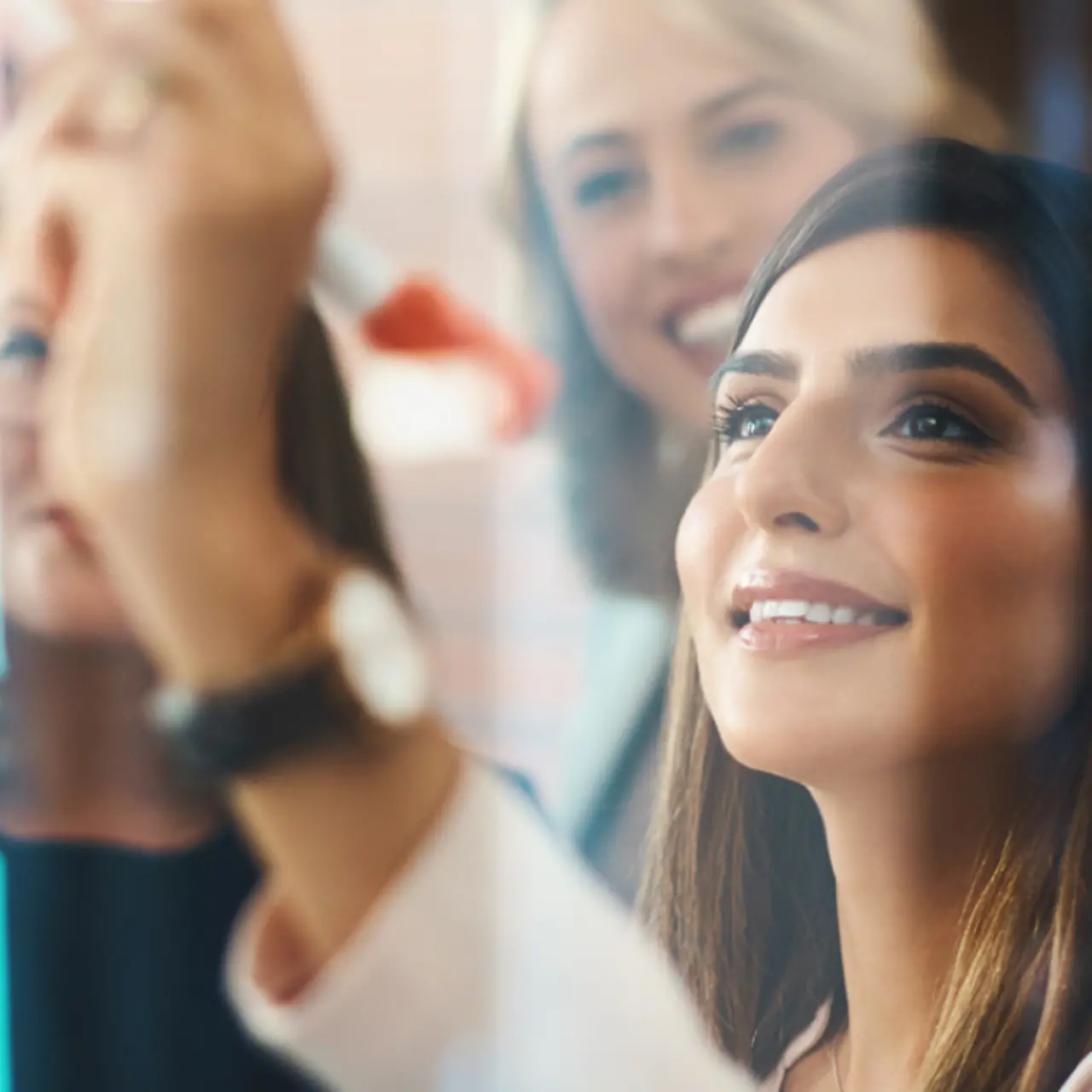 Meeting in office. Woman writing on post-it. People in the background blurred.