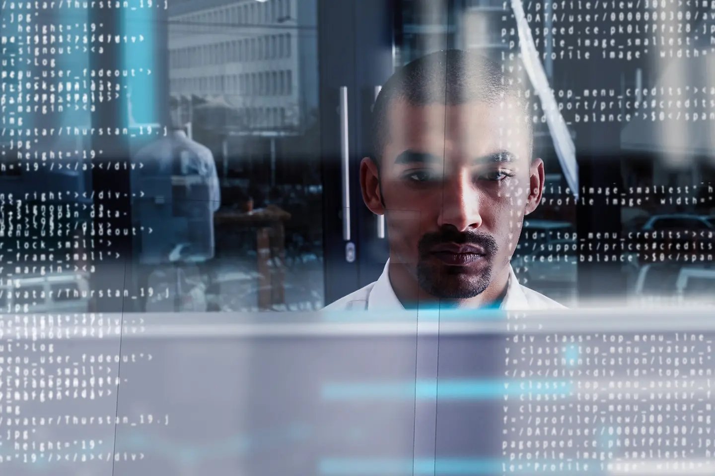 Hombre en primer plano mirando textos de datos en una pantalla transparente