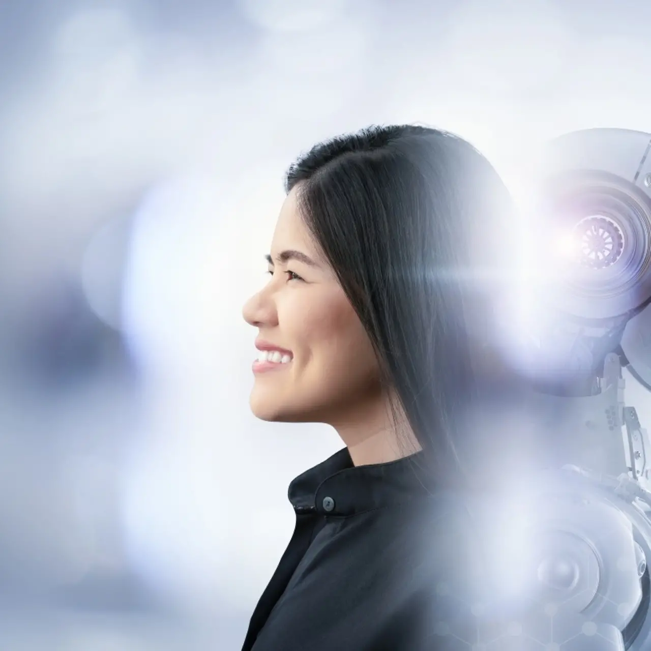 A smiling woman is leaning back to back with a robot.