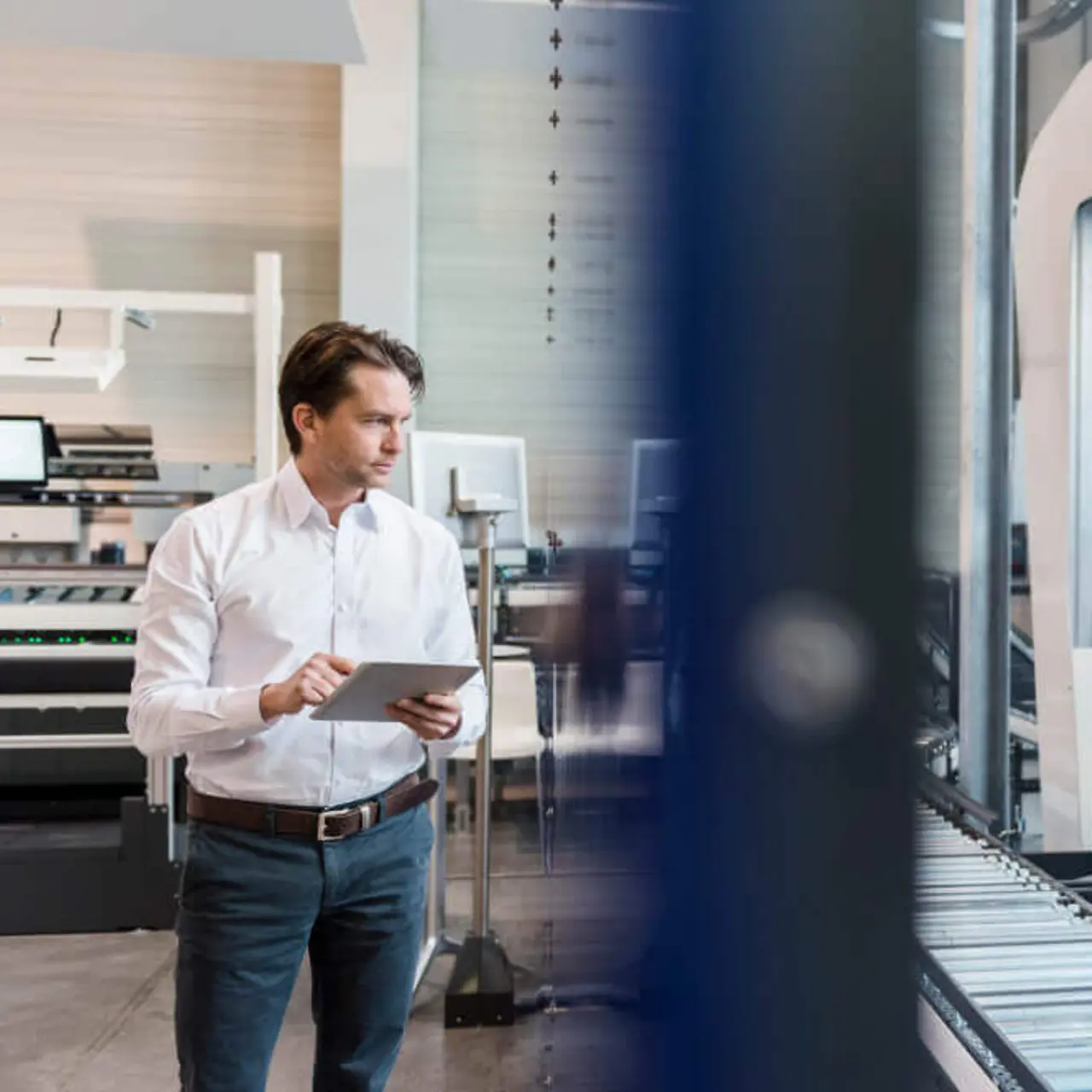 Um empresário está usando um tablet na linha de montagem em uma fábrica