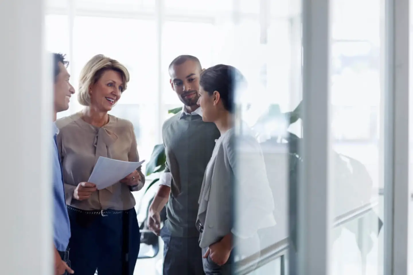 Vier Personen, die in einem Büro stehen und sich unterhalten 
