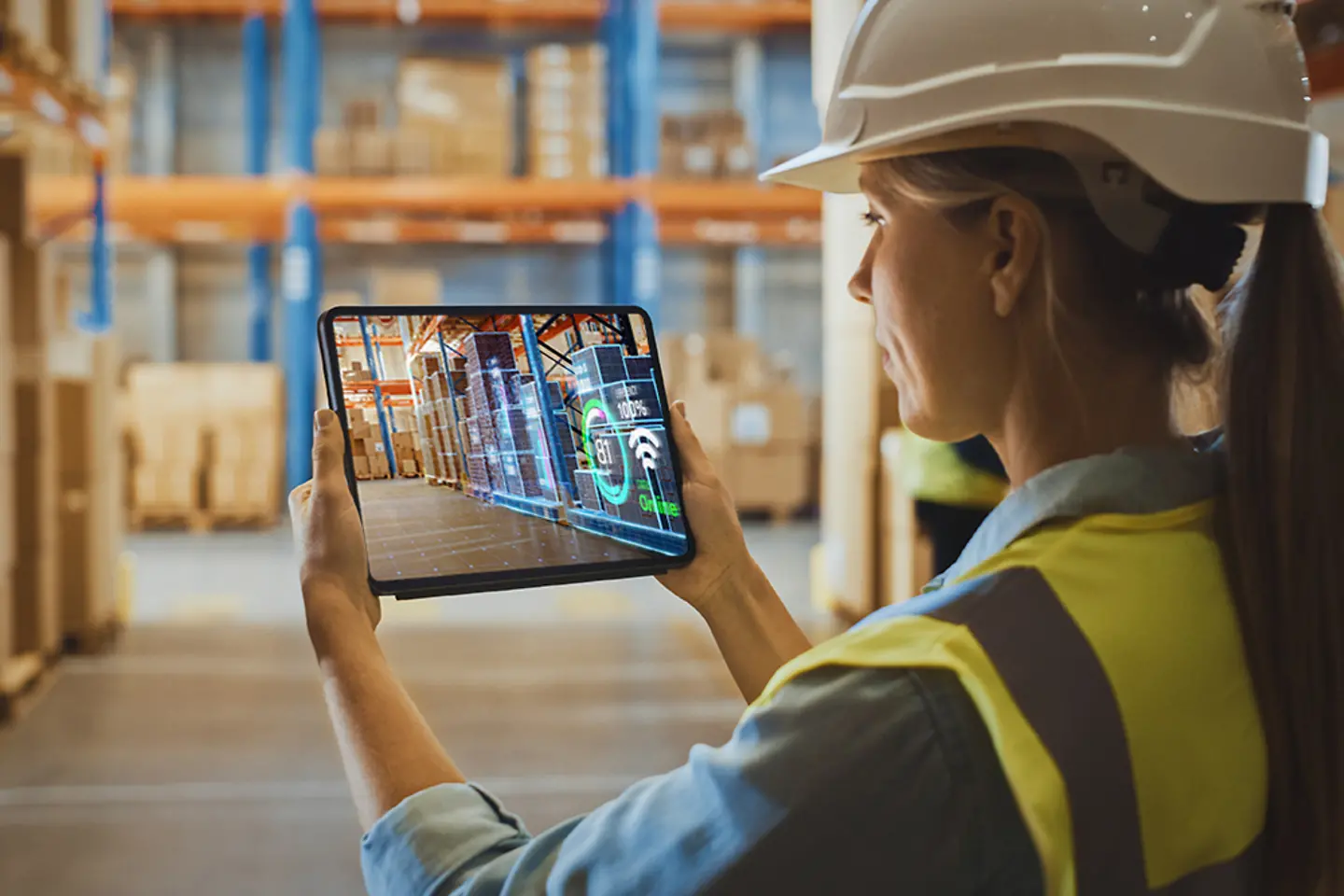 Junge Mitarbeiterin, die im Lagerhaus mittels Augmented Reality mit einem digtitalen Tablet Inventur macht