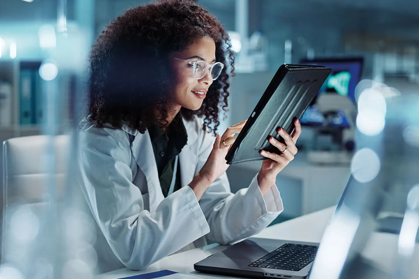 Woman with glasses smiles and operates tablet